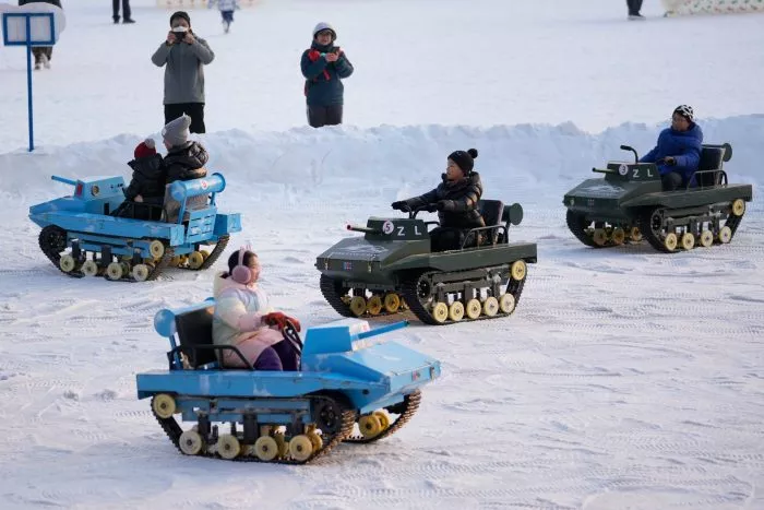 Kinder sausen in Panzer-Schneekarts durch den Longtan Park zum Mondneujahr