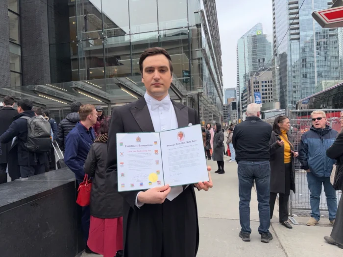 Toronto, 29. März 2026 – Ein Shen-Yun-Moderator zeigt vor dem Four Seasons Centre for the Performing Arts eine Ehrenurkunde der liberalen Abgeordneten Judy Sgro. Foto: Xinxin Teng/The Epoch Times