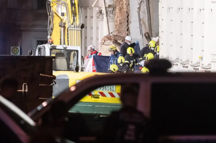 Einsatzkräfte der Feuerwehr tragen hinter Sichtschutz eine Leiche aus dem Trümmerfeld eines eingestürzten Hauses in Görlitz.