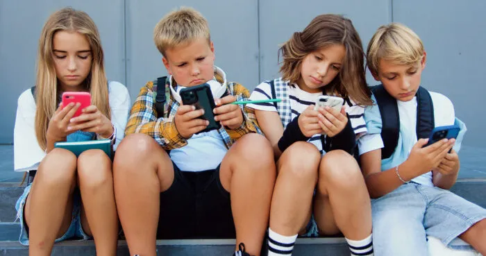 Im Banne des Handys: Kinder, die gemeinsam einsam in den Bildschirm glotzen. Foto: Sergii Kozii/iStock
