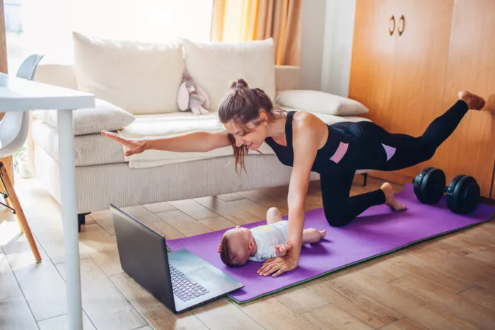 Junge Mutter mit Baby übt Gymnastik. Foto: Maryviolet/iStock