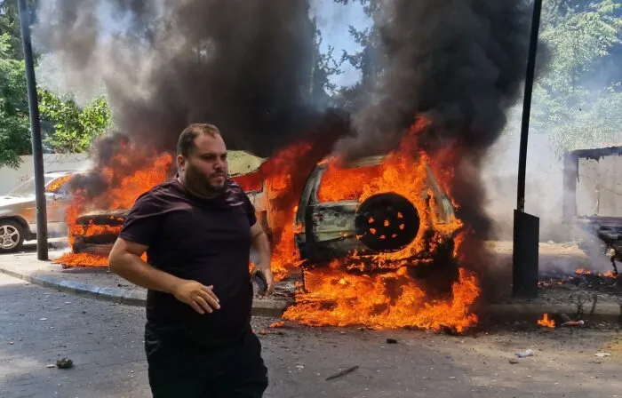 Ein Mann läuft vor brennenden Autos, die bei einem israelischen Luftangriff in der libanesischen Hafenstadt Sidon in Brand geraten sind.