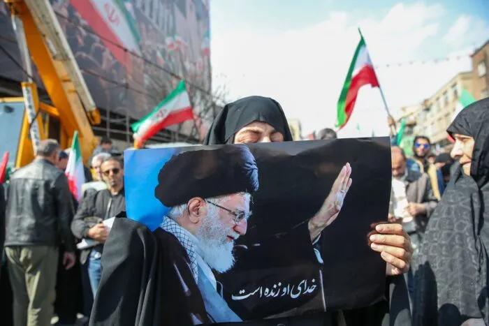 Eine Trauernde hält beim Begräbnis des von Israel getöteten Generalsekretärs des iranischen Sicherheitsrats, Ali Laridschani, ein Bild des ebenfalls getöteten Obersten Führers Ajatollah Ali Chamenei in die Höhe.