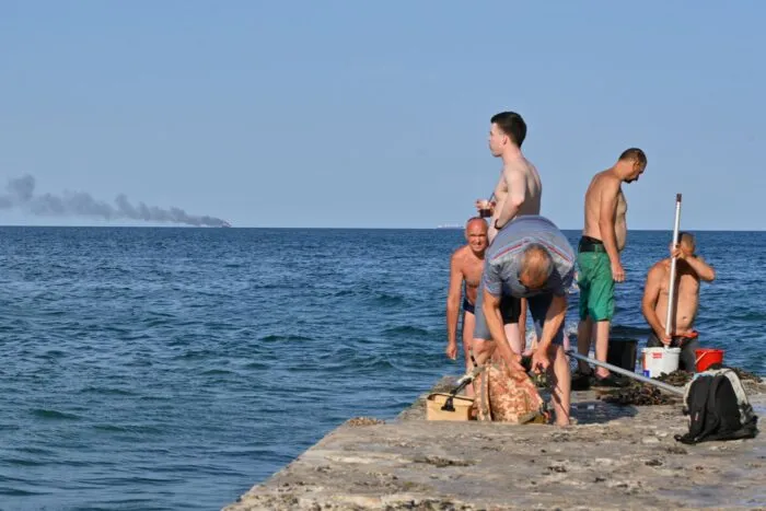 Menschen in Odessa sonnen sich, während am Horizont im Schwarzen Meer der brennende Getreidetransporter «Golden Leo» zu sehen ist. (Archivbild)