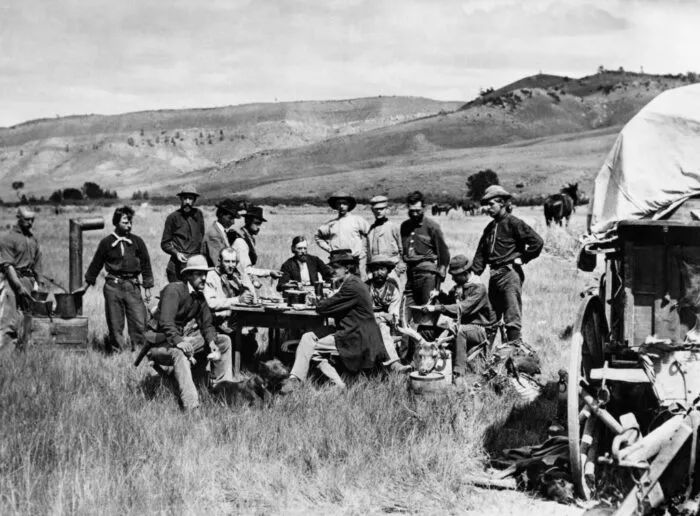 Mitglieder des US-amerikanischen Hayden Geological Survey essen am 24. August 1870 in ihrem Lager in Red Buttes, Wyoming-Territorium, zu Mittag. Am Tisch, dem Betrachter zugewandt, sitzt der Geologe Ferdinand Vandeveer Hayden; rechts daneben der offizielle Fotograf des Surveys, William Henry Jackson. Die von Hayden geleitete Gruppe erkundete die Region im Nordwesten Wyomings, die später zum Yellowstone-Nationalpark wurde. Foto: ACME / AFP via Getty Images