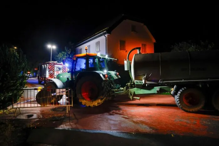 Die Feuerwehr wässert Wiesen vor Wohnbebauung.