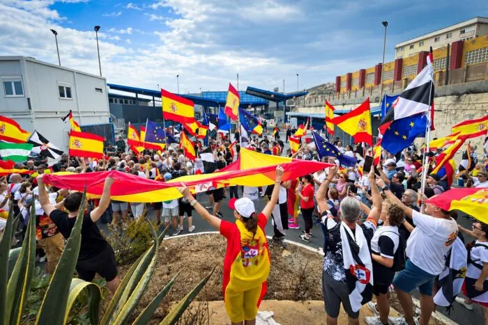 Demonstranten spannen eine große spanische Flagge auf und schwenken spanische Flaggen sowie Flaggen von Ceuta und der EU vor dem Grenzübergang Tarajal am Ende eines Marsches in Ceuta, Spanien, am 20. September 2026.