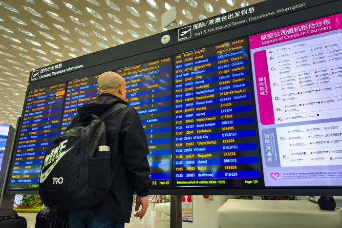 13. April 2025: Ein Reisender vor der digitalen Abflugtafel am internationalen Flughafen Shenzhen Bao’an.