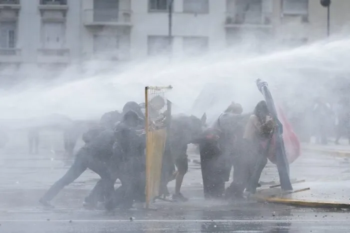 Demonstranten in Buenos Aires suchen Deckung, während die Polizei bei einer regierungskritischen Demonstration einen Wasserwerfer einsetzt.